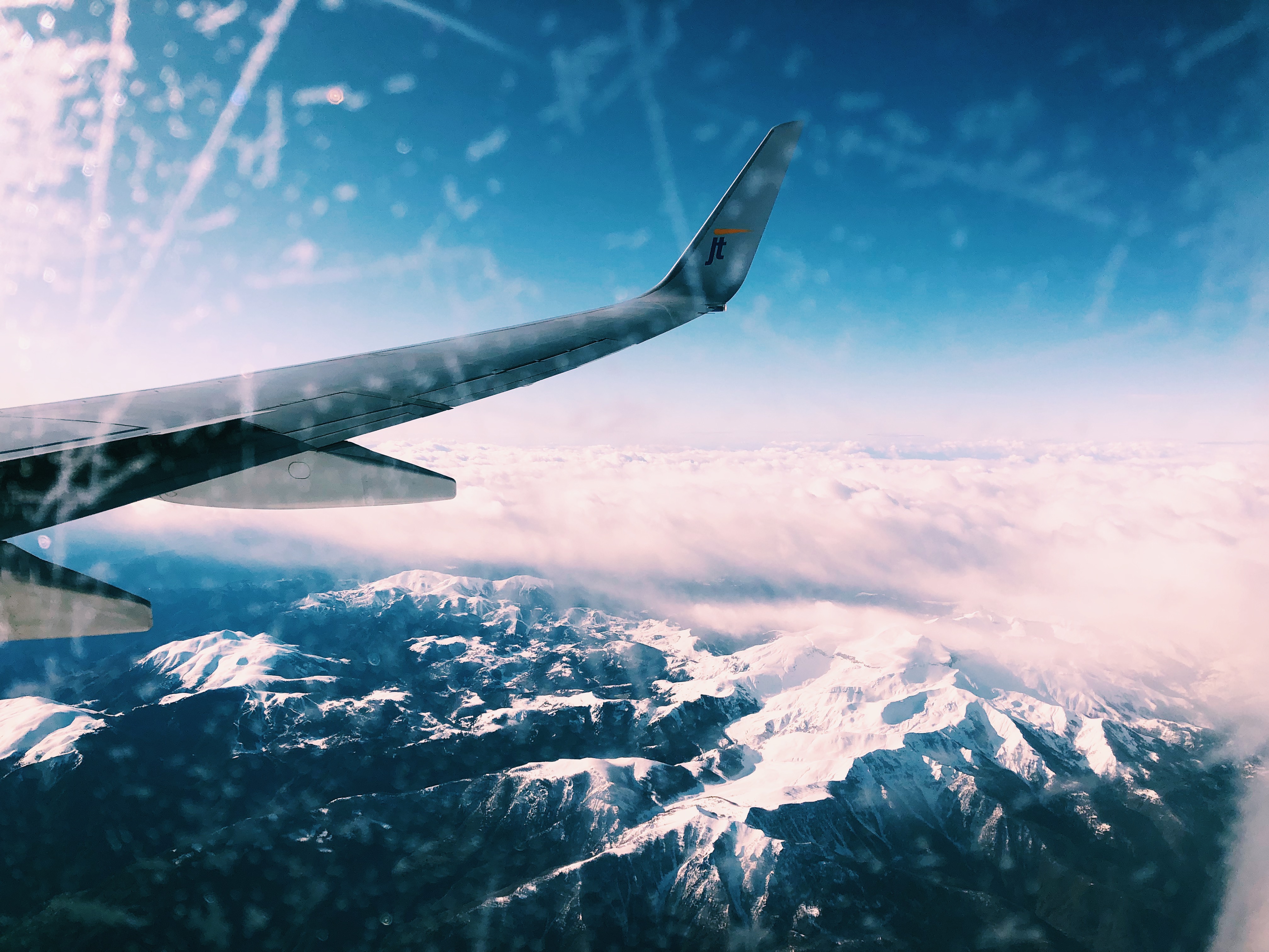 Picture taken through plane window showing the wing of the plane and the snow-covered French Alps